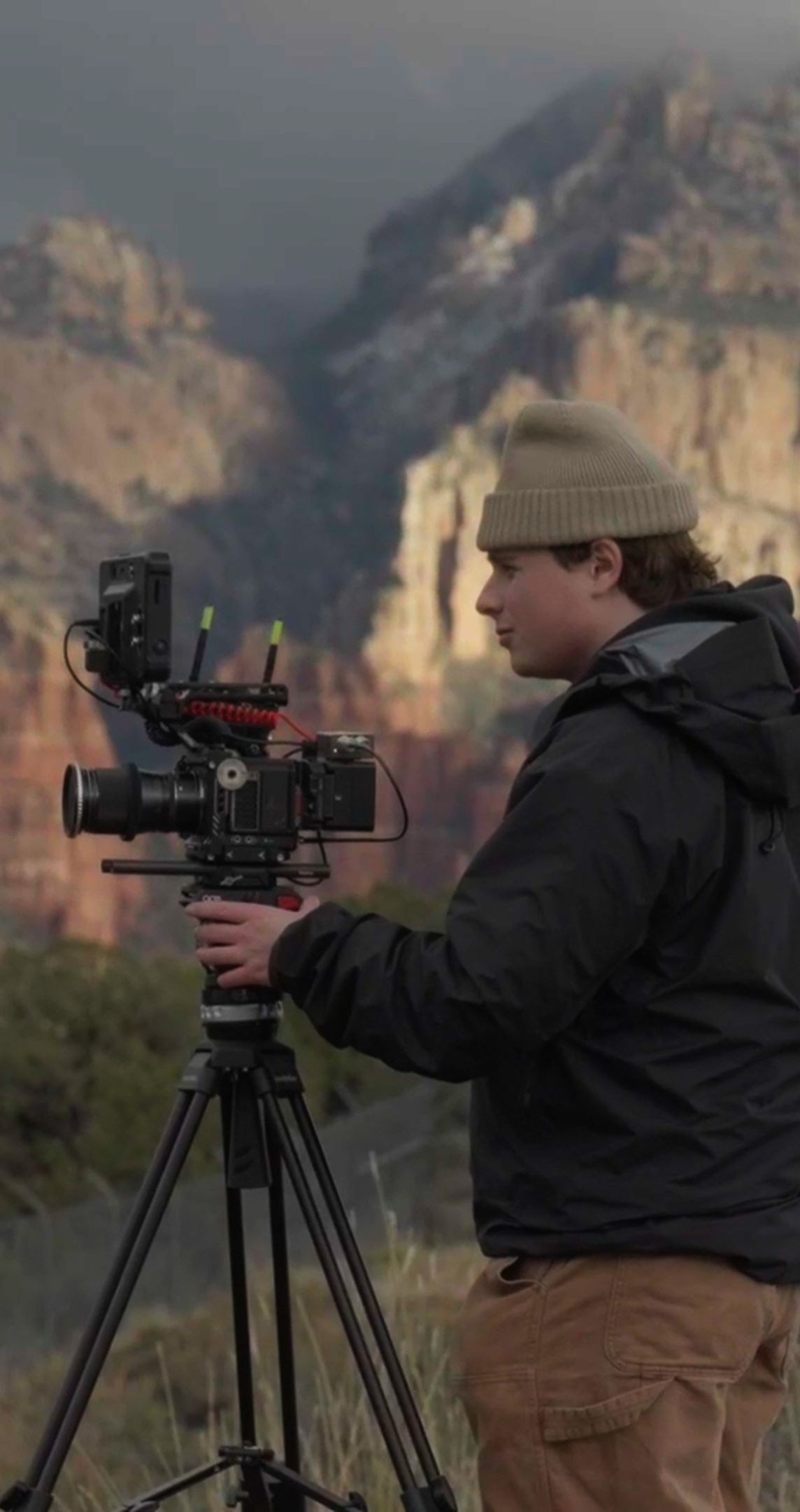 Cyan Lens camera operator filming in front of red rock mountains