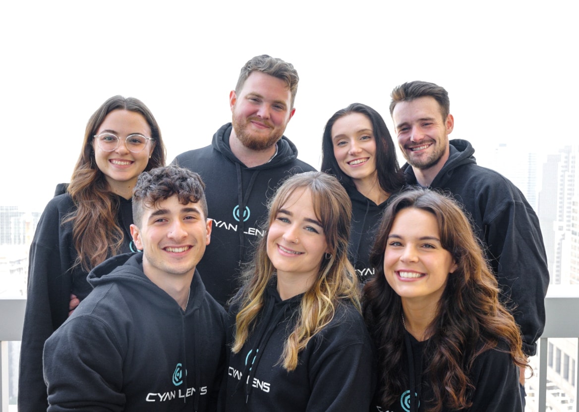 Seven members of the Cyan Lens team in matching Cyan Lens hoodies